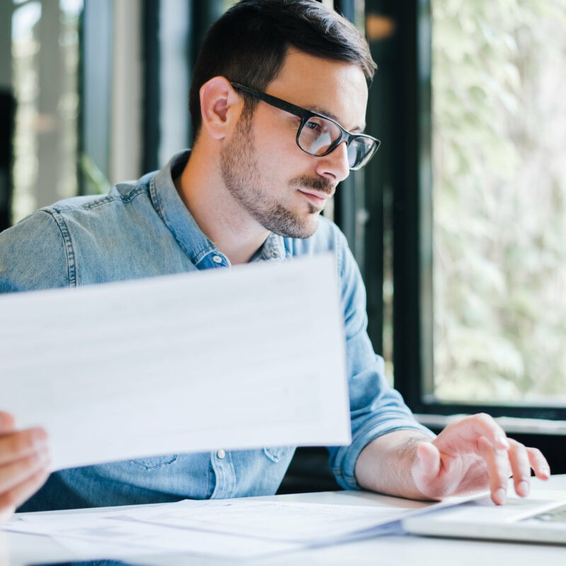 homme lunette ordinateur feuille main