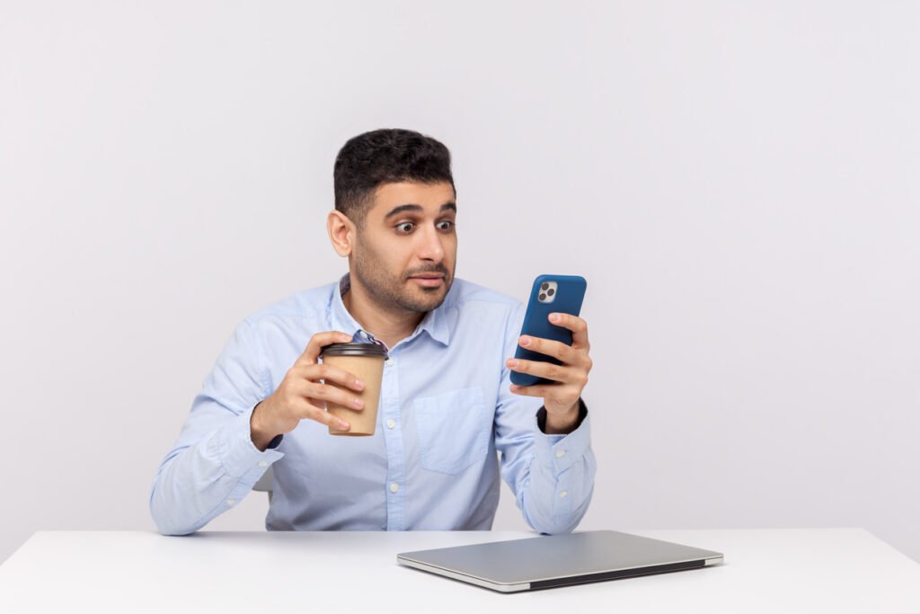 homme brun smartphone café surpris accroche