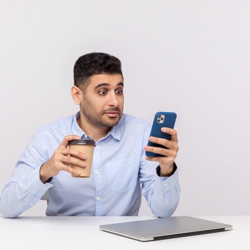 homme brun smartphone café surpris accroche