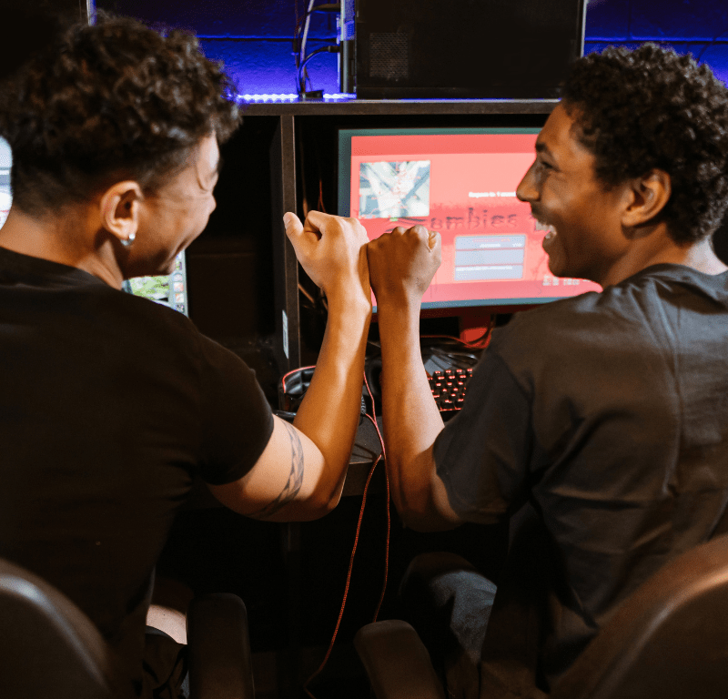 Deux homme qui se tapent la main devant leur ordinateur.