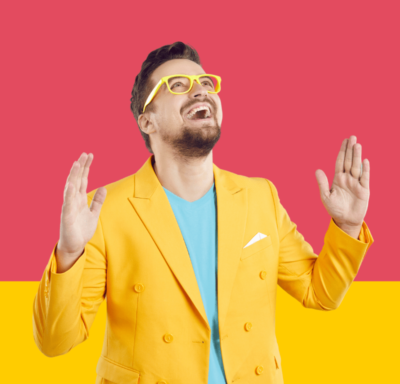 Homme costume jaune tee-shirt vert mains en l'air sur fond corail avec bande jaune