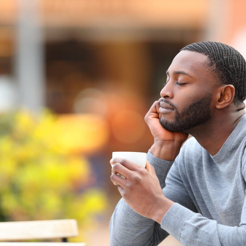 Homme noir pull gris fermant les yeux en tenant sa tasse de café - personnaliser la relation client